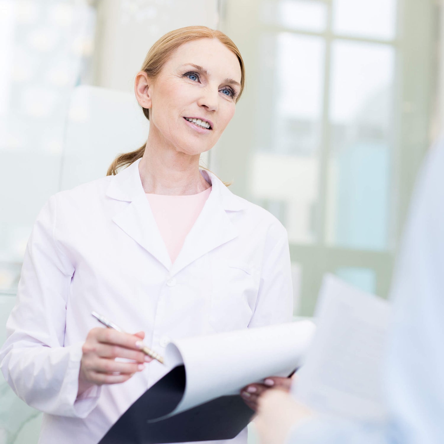 Female doctor in a white doctors' coat holding a clipboard